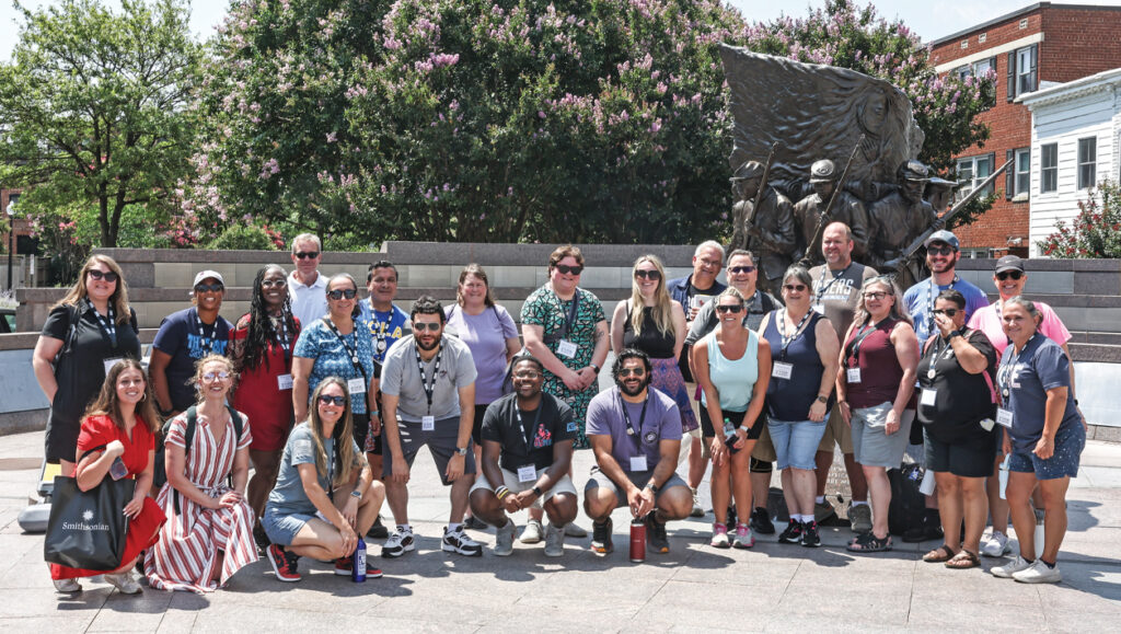 A group of people stand in front of a statue and pose for the camera.